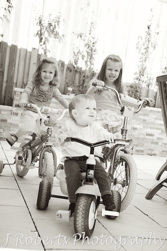sisters riding bikes and tricycles - family portrait photography sydney